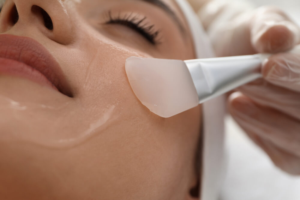 Young woman during face peeling procedure in salon