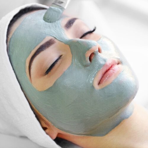 Young woman with nutrient facial mask in beauty salon